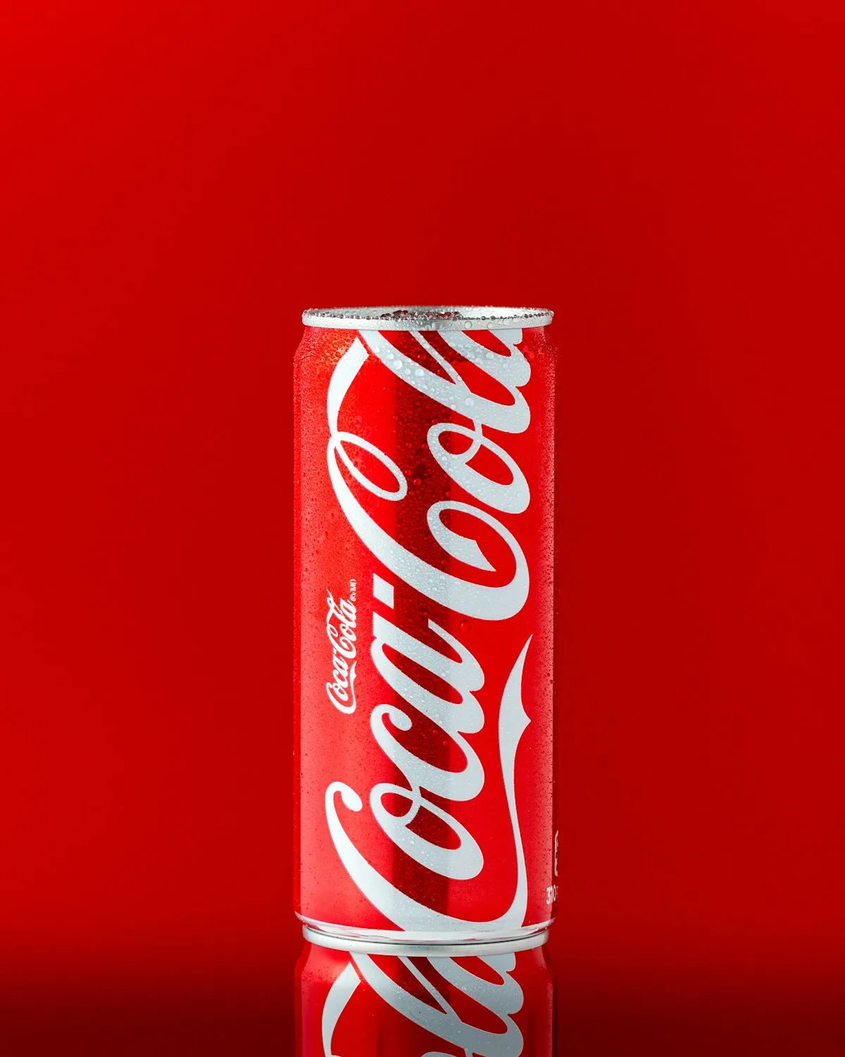 Two cola glasses with ice on a reflective surface