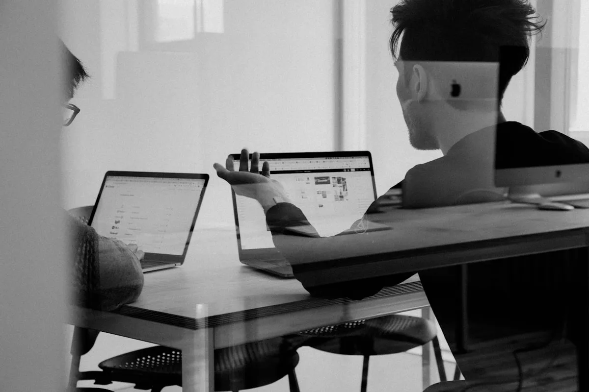 Open plan office with people collaborating at desks with laptops and coffee cups